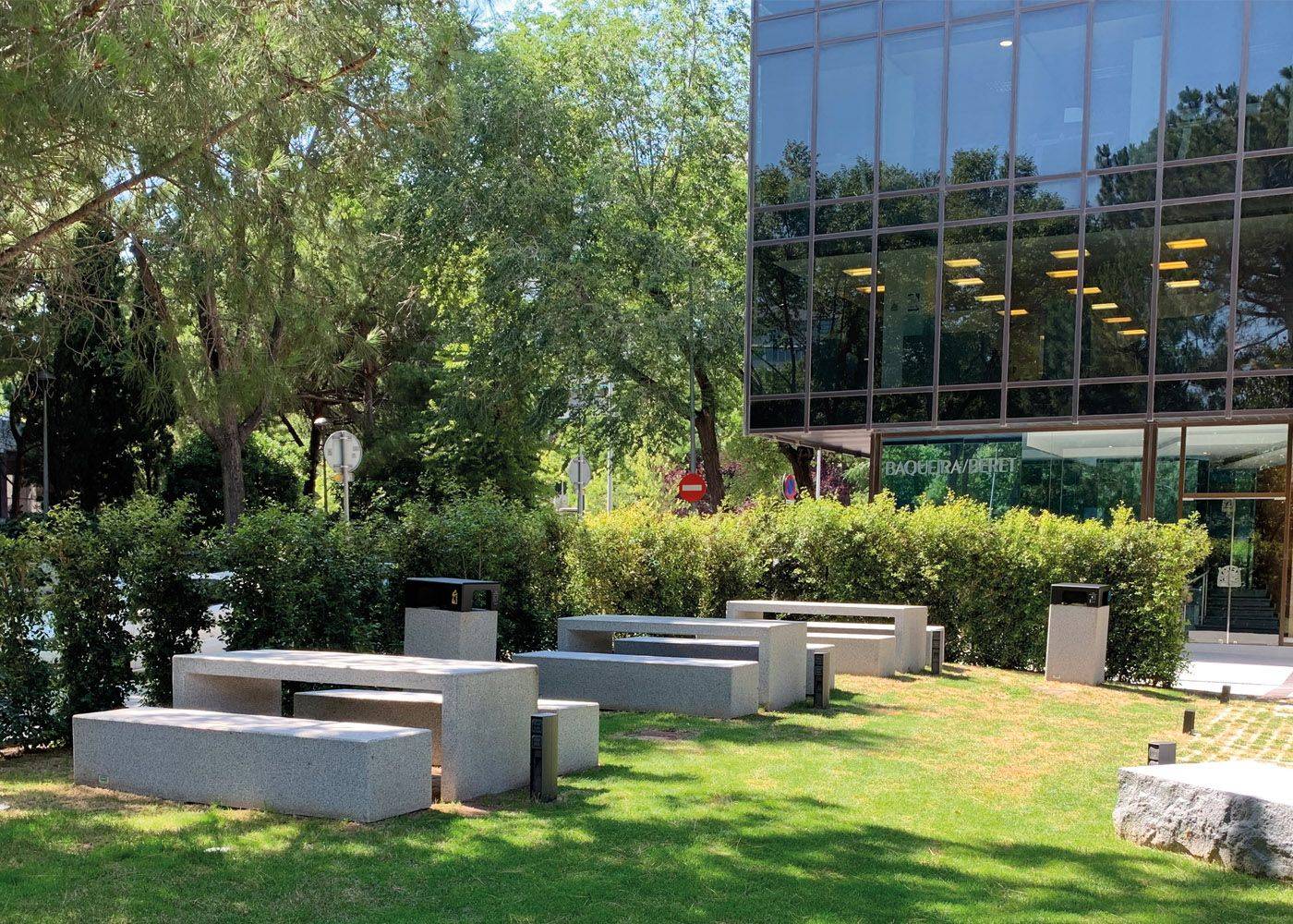 Conjunto de mesas y bancos de hormigón en un entorno corporativo al aire libre, integrando robustez y diseño minimalista en el espacio exterior.