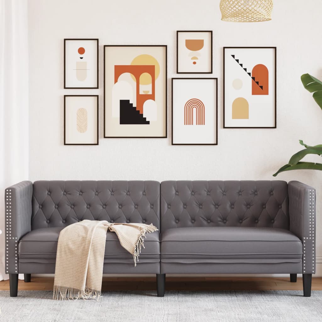 Sofá Chesterfield de 3 plazas en gris con cojín y arte moderno en la pared, ideal para descanso y elegancia.