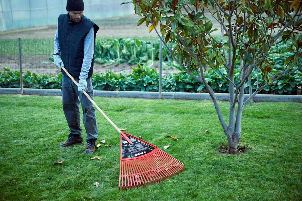 Escoba extragrande Bellota 3034-32CM en uso barriendo hojas sobre el césped