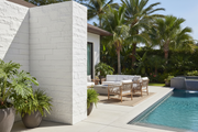 Esquina de muro rematada con Piedras de Angulo Poblet color blanco en un patio de lujo con piscina y muebles de exterior