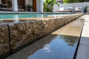Borde de piscina revestido con piedra artificial tratada con el hidrófugo de efecto mojado Levante - Vetonek